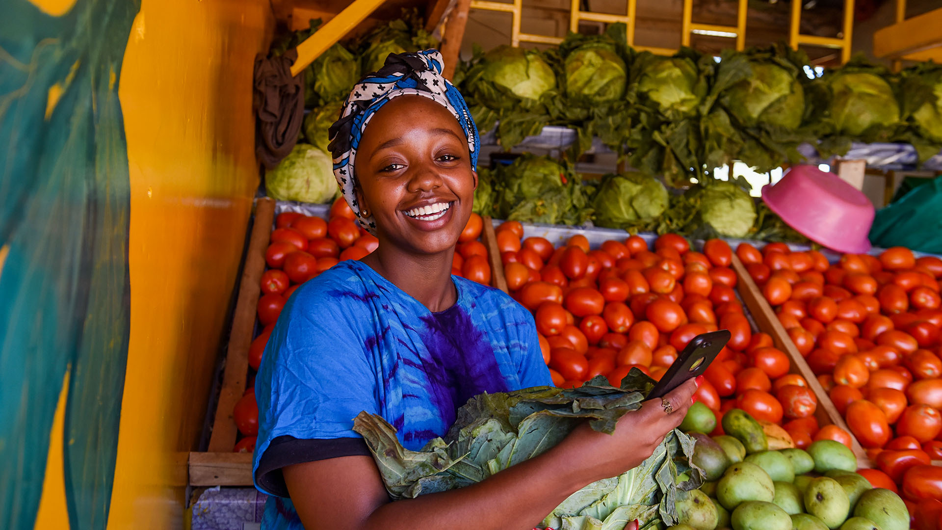 A woman smiles after receiving payment for groceries in Kiambu, Kenya